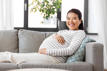 Image showing happy pregnant asian woman sitting on sofa at home