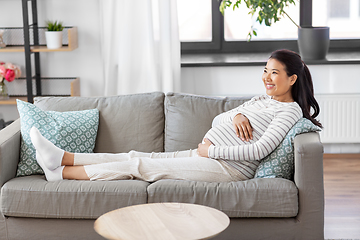 Image showing happy pregnant asian woman sitting on sofa at home