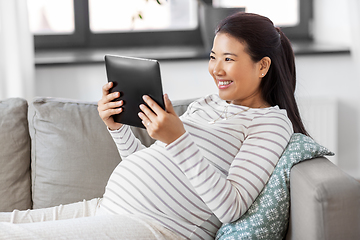 Image showing happy pregnant asian woman with tablet pc at home