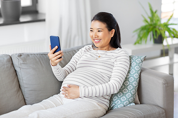 Image showing happy pregnant woman with smartphone at home