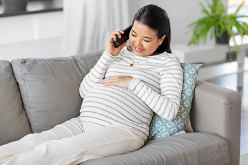 Image showing happy pregnant woman calling on smartphone at home