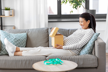 Image showing happy pregnant woman opening gift box at home