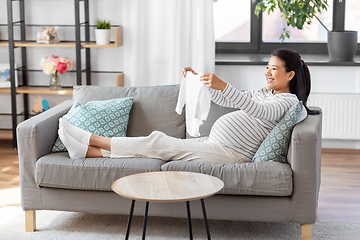 Image showing happy pregnant woman with baby's bodysuit at home