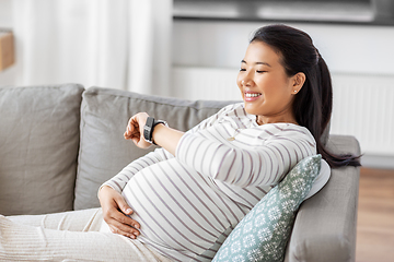 Image showing happy pregnant woman with smart watch at home