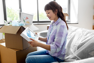 Image showing happy woman unpacking boxes and moving to new home