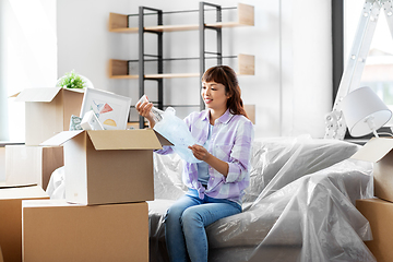 Image showing happy woman unpacking boxes and moving to new home