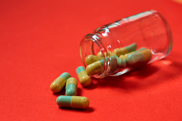 Image showing Pills spilling out of pill bottle on red. Top view with copy space. 