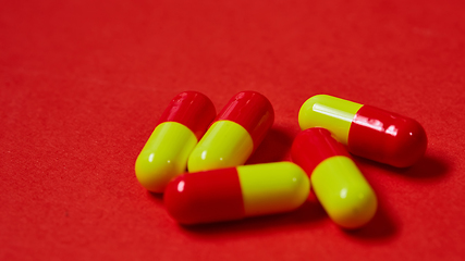 Image showing Pills spilling out of pill bottle on red. Top view with copy space. 