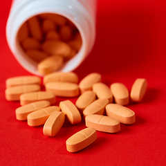 Image showing Pills spilling out of pill bottle on red. Top view with copy space. 