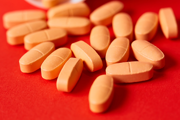 Image showing Pills spilling out of pill bottle on red. Top view with copy space. 