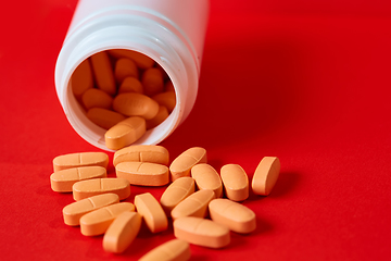 Image showing Pills spilling out of pill bottle on red. Top view with copy space. 