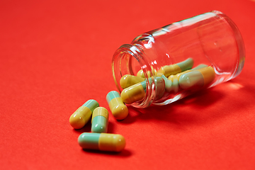 Image showing Pills spilling out of pill bottle on red. Top view with copy space. 