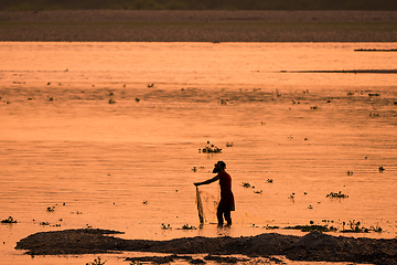 Image showing Asian Woman fishing in the river, silhouette at sunset