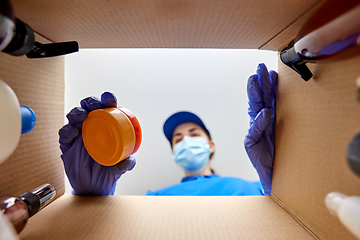 Image showing woman in mask packing parcel box with cosmetics