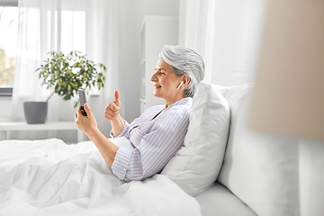 Image showing senior woman with phone having video call in bed