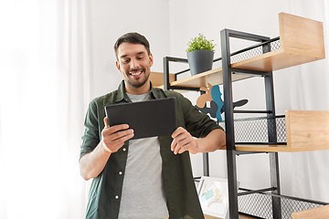 Image showing happy smiling man with tablet pc at shelf at home