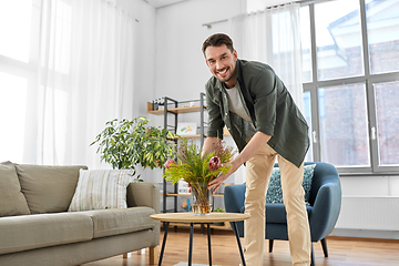 Image showing man placing flowers on coffee table at home