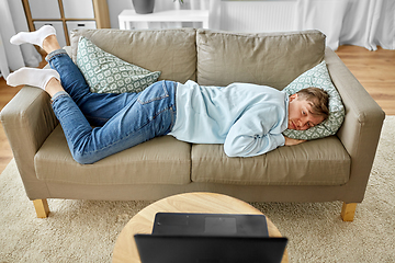 Image showing bored man with laptop lying on sofa at home