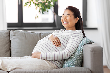 Image showing happy pregnant asian woman sitting on sofa at home