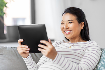 Image showing happy pregnant asian woman with tablet pc at home