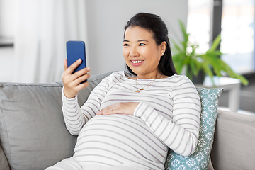 Image showing happy pregnant woman with smartphone at home