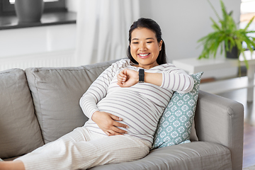 Image showing happy pregnant woman with smart watch at home