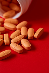 Image showing Pills spilling out of pill bottle on red. Top view with copy space. 