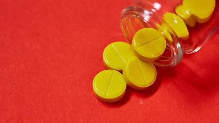 Image showing Pills spilling out of pill bottle on red. Top view with copy space. 