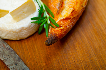 Image showing French cheese and fresh  baguette on a wood cutter