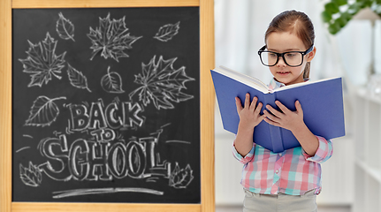 Image showing little student girl in eyeglasses reading book