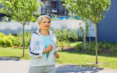 Image showing sporty senior woman running along in city