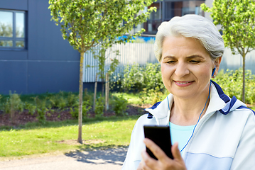 Image showing sporty senior woman with earphones and smartphone