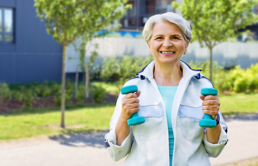 Image showing senior woman with dumbbells exercising in city