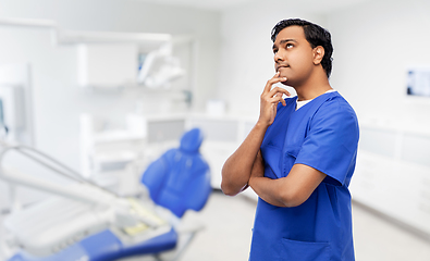 Image showing thinking indian male doctor at dental office