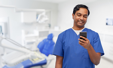 Image showing smiling doctor using smartphone at dental office