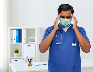 Image showing stressed indian doctor in mask having headache