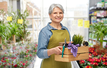 Image showing senior woman with garden tools in gardening center