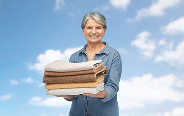 Image showing smiling senior woman with clean fresh bath towels