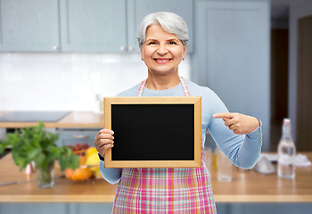 Image showing smiling senior woman in apron with chalkboard