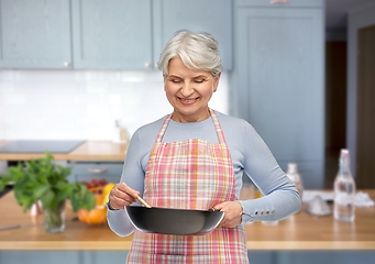 Image showing smiling senior woman in apron with frying pan