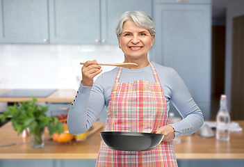 Image showing smiling senior woman in apron with frying pan