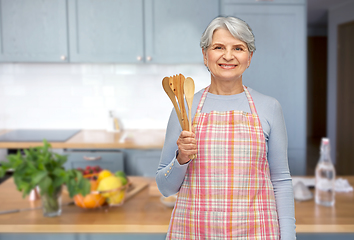 Image showing smiling senior woman in apron with wooden spoons