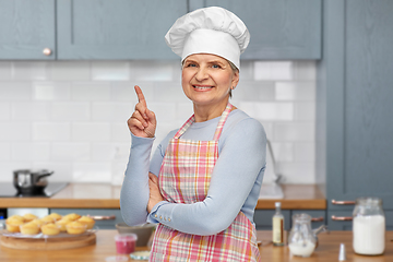 Image showing smiling senior woman or chef pointing finger up