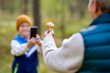 Image showing grandson photographing grandmother with mushroom
