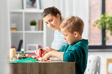 Image showing mother and son making pictures of autumn leaves