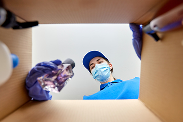 Image showing woman in mask packing parcel box with cosmetics