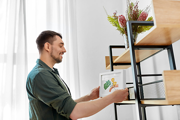 Image showing man decorating home with picture in frame