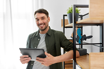 Image showing happy smiling man with tablet pc at shelf at home