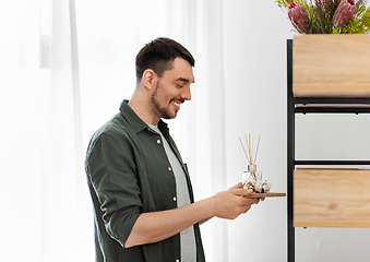 Image showing man placing aroma reed diffuser to shelf home