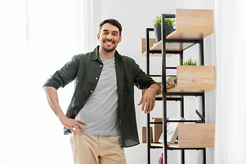 Image showing happy smiling man standing at shelf at home